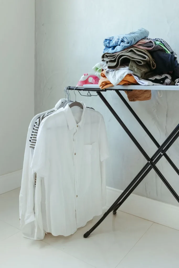 Pressed white shirts hanging beside an ironing board